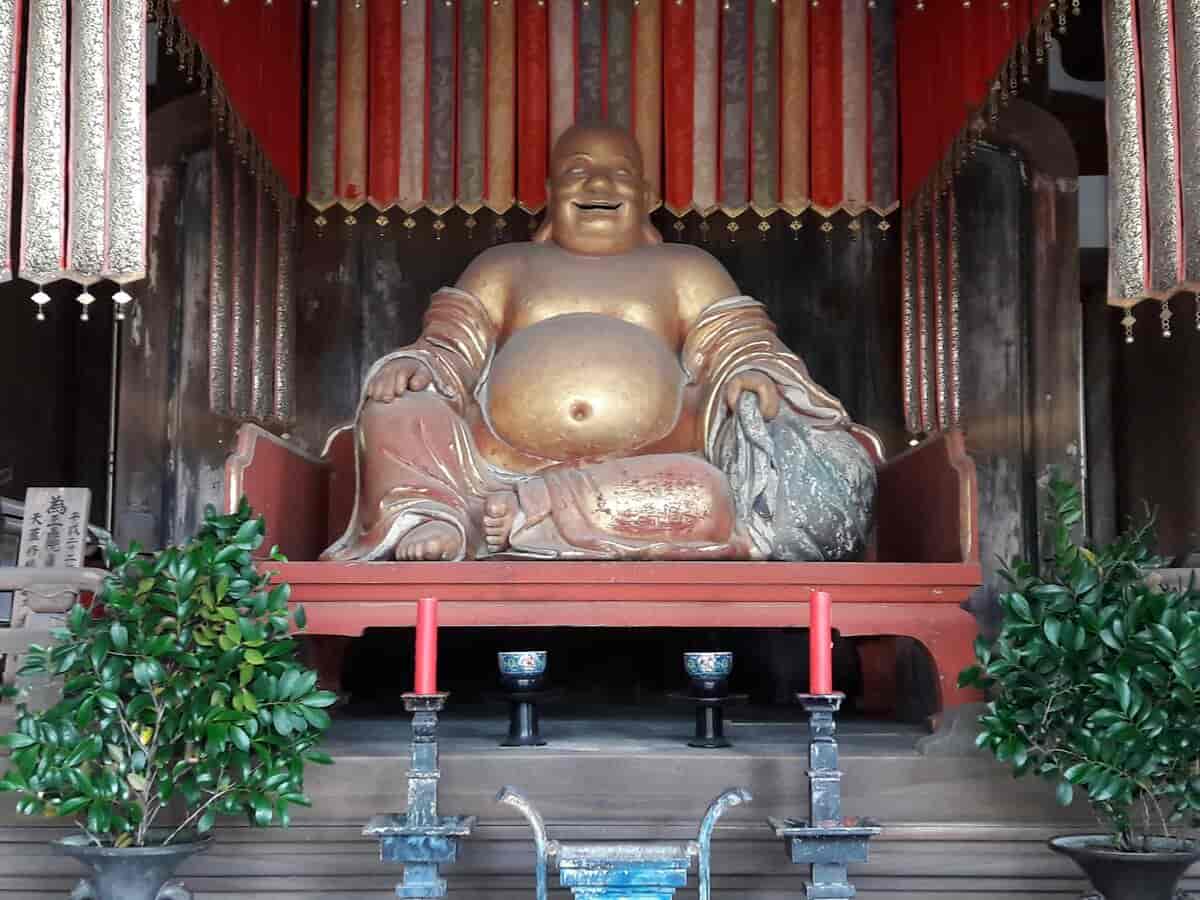 Som i kinesiske buddhisttempler møder Budai (japansk Hotei) den besøgende ved indgangen. Han er også en af de syv lykkeguder i Japan og spreder glæde, vellevned og gavmildhed.