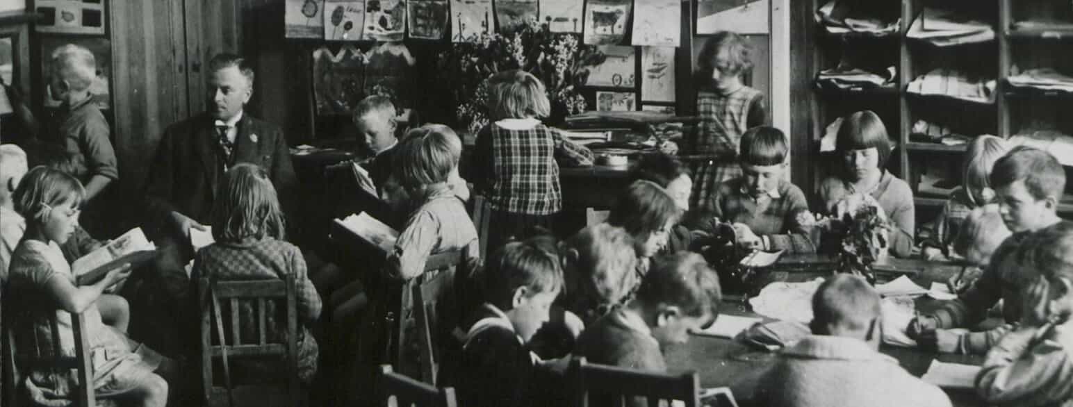 Vanløse Skole 1924 - 1928. Lærer Olaf de Hemmer Egeberg sidder blandt sine elever i klasseværelset, hvis indretning adskilte sig fra den gængse