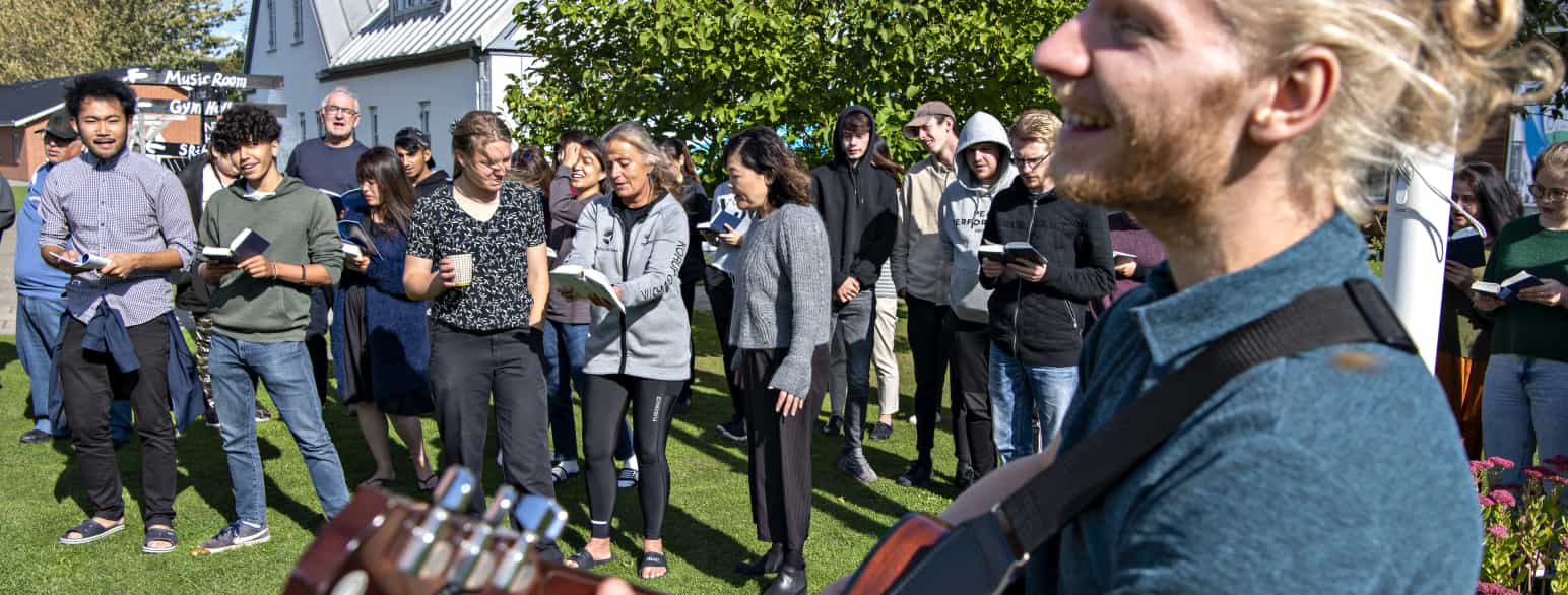 Lærere og elever er samlet til udendørs fællessang på Nordfyns Højskole i Harritslev