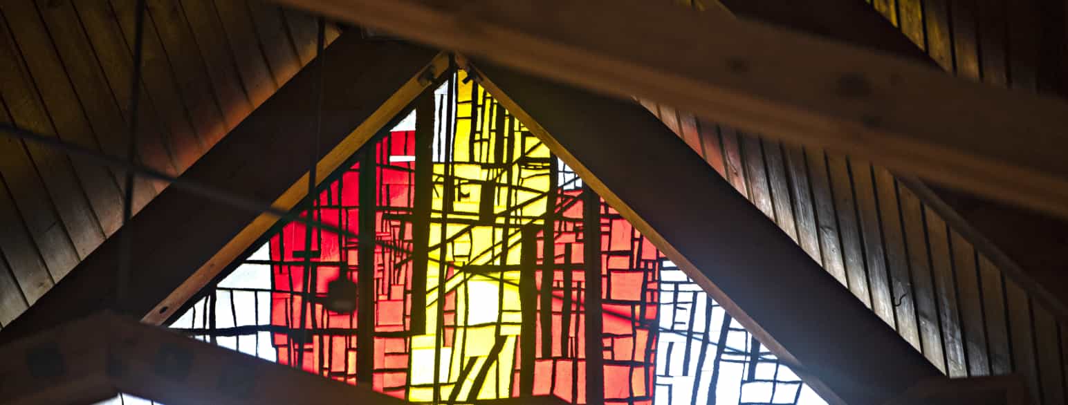 Glasmosaikkerne i Hundige Kirkes gavle fylder kirkerummet med et varmt gult og rødt lys