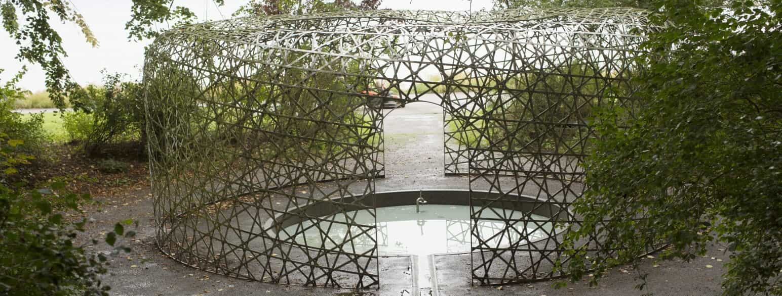 Olafur Elíasson har skabt værket "5-dimensionel pavillon", som er en fortolkning af den naturlige kilde, der siden 1906 har udgjort et springvand i Strandparken i Holbæk