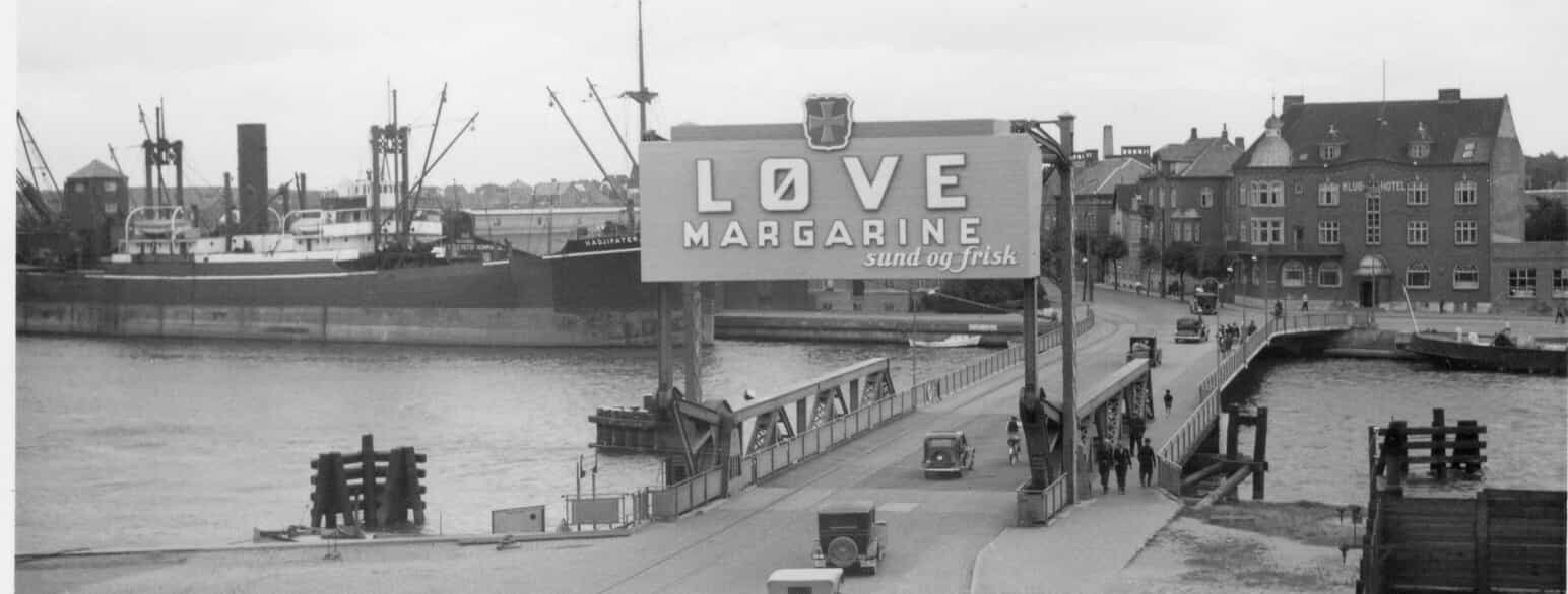 Et stort reklameskilt er blevet stillet op på Halsskov Bro med ordene »Løve Margarine – sund og frisk« fra 1925 
