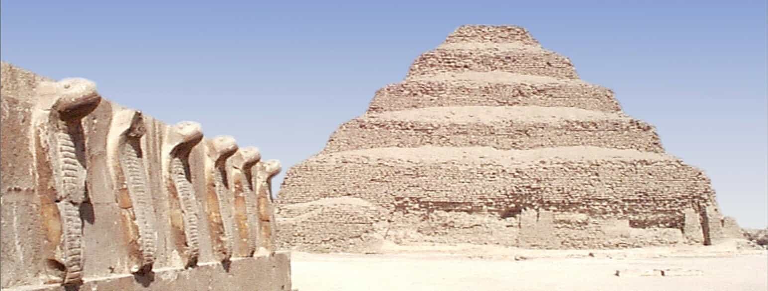 Djosers trinpyramide i Saqqara er et af Egyptens vigtigste bygningsværker. I forgrunden ses en mur med cobraer.