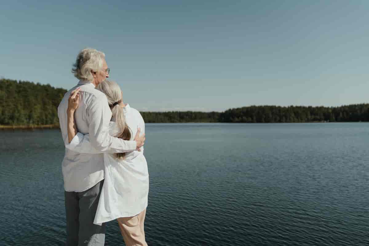 Et ældre par omfavner hinanden foran en sø