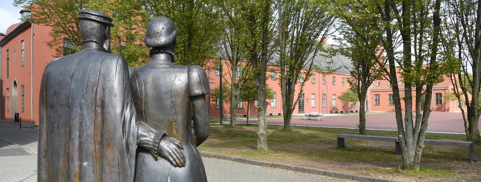 Birgitte Gøye og ægtefællen Herluf Trolle betragter deres livsværk, Herlufsholm. Skulptur af Eva Steen Christensen