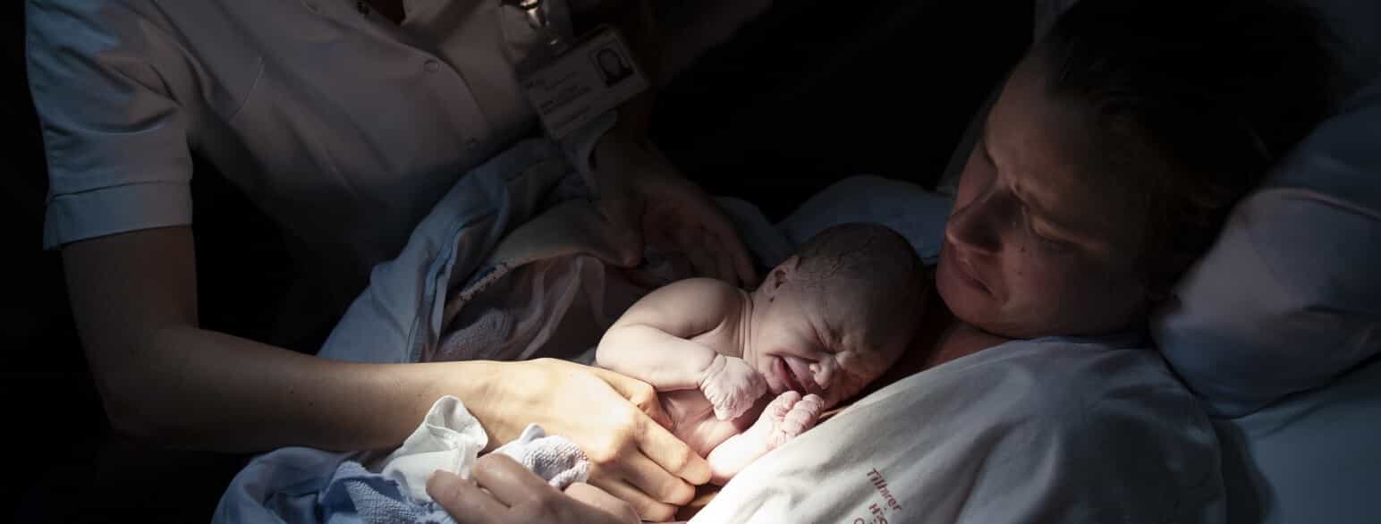 En nyfødt baby holdes for første gang af sin mor