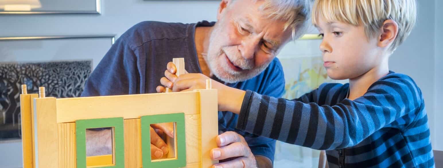 Bedstefar og barnebarn bygger et dukkehus sammen.