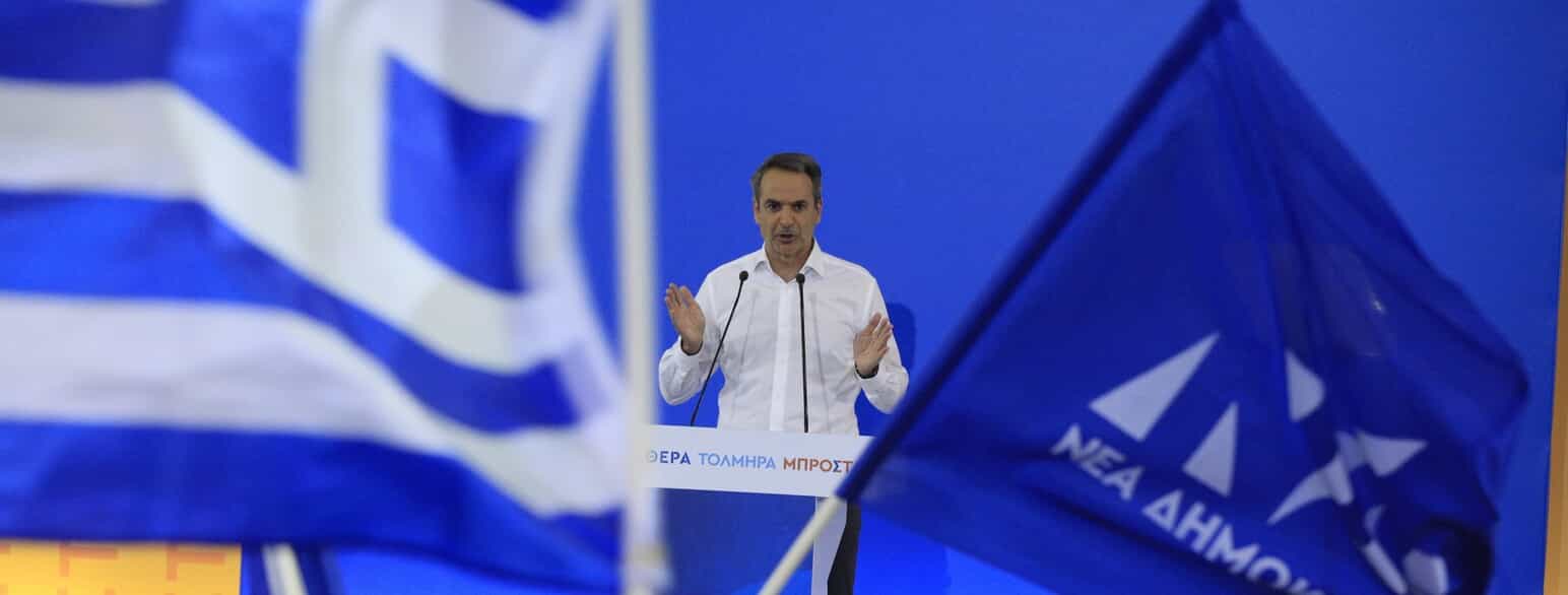 Premierminister Kyriakos Mitsotakis på et valgmøde i en sportshal i Egaleo, Athen, den 24. april 2023 mellem det græske flag (tv.) og et flag med partiets nye logo.