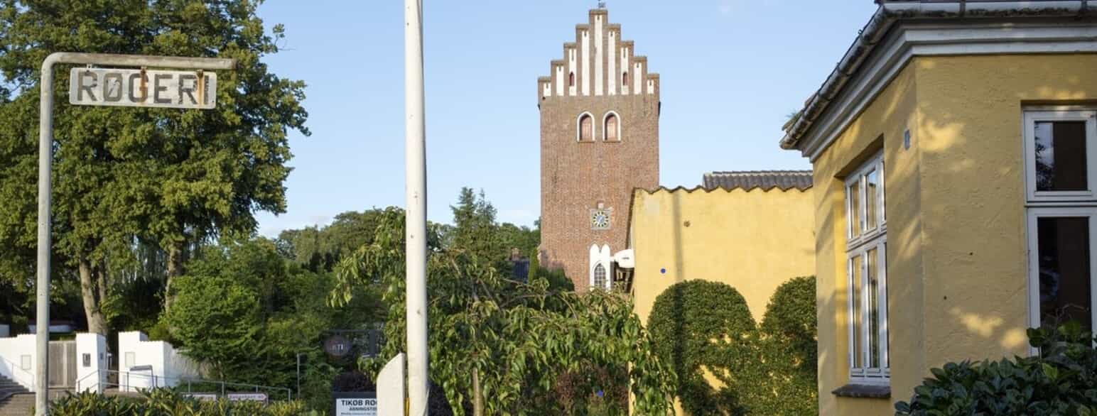 Fra en banke i Tikøbs sydøstkant dominerer teglstenskirkens kraftige tårn bybilledet.
