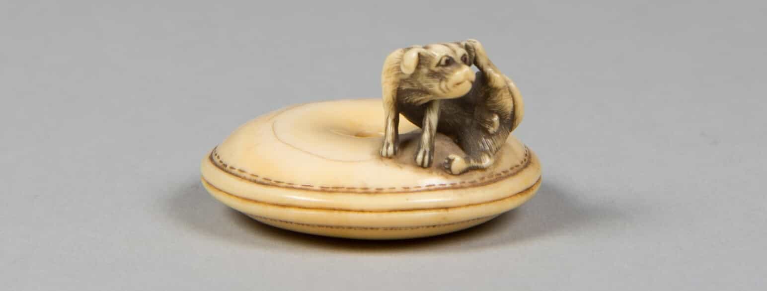 lille elfenbensfigur der forestiller en hund på en pude