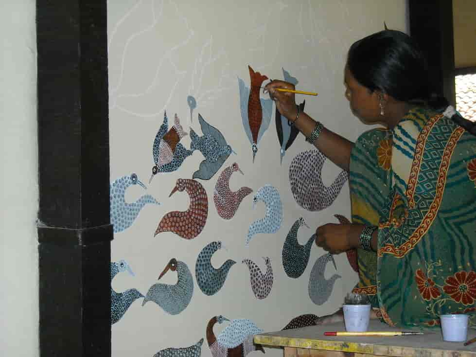 Kvinde fra gond-folket maler på indvending husmur