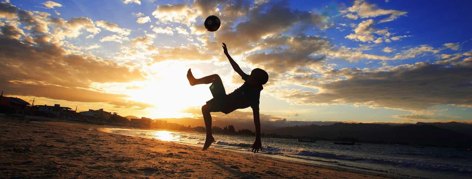 Dreng spiller fodbold på en strand i Brasilien
