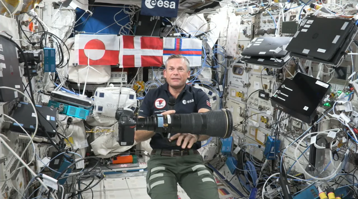 Andreas Mogensen på rumstationen i 2023. Foran ham svæver  et Nikon D5 kamera med 400 mm linse.