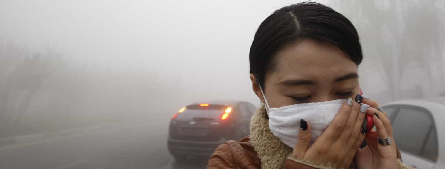 Med mundbind og hænderne forsøger en kvinde i byen Harbin i det nordøstlige Kina at mindske mængden af indåndede, skadelige partikler og gasser