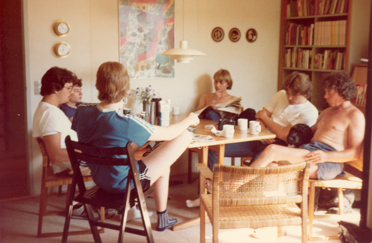 En gruppe mennesker sidder omkring et bord og læser avis