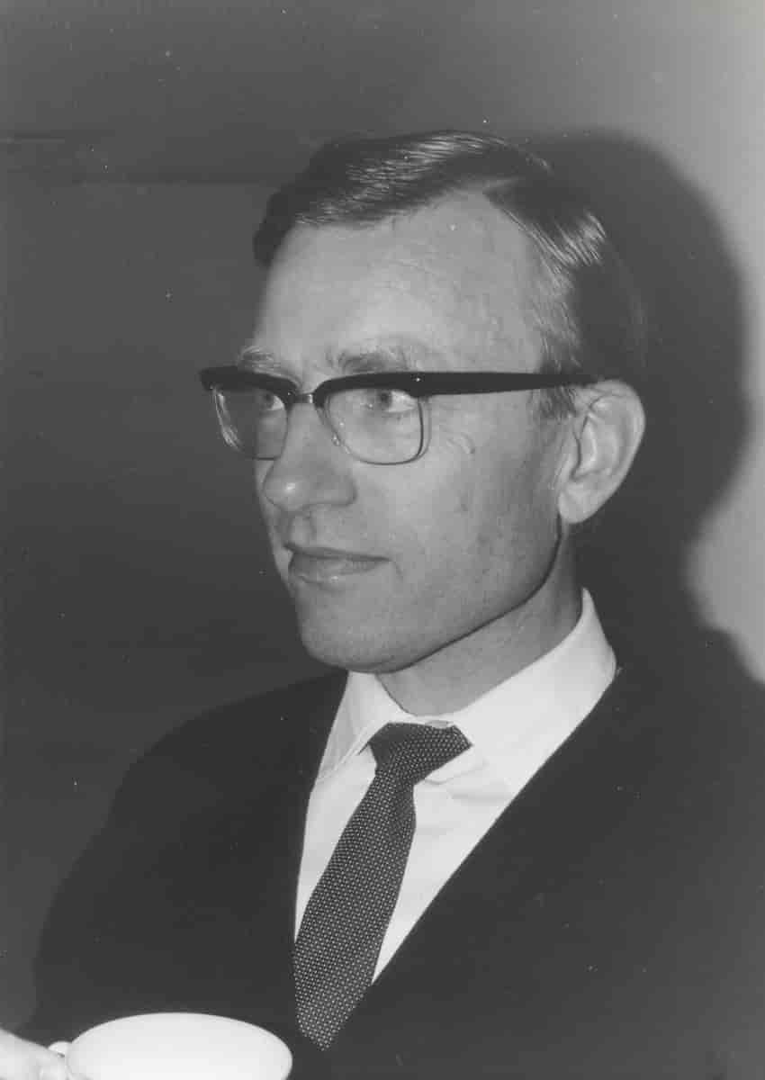 Sort-hvidt fotografi i portrætformat af Bent Fuglede, beskåret under skuldrene. Fuglede har på fotografiet sideskilning og briller og er iført jakke, skjorte og slips.